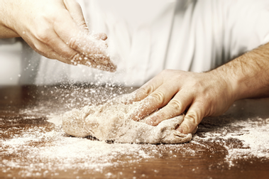 Hands kneading bread dough on a floured counter